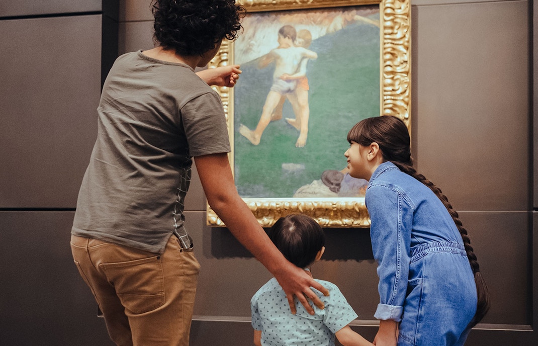 Visitors admiring a painting at Louvre Museum Abu Dhabi exhibit.