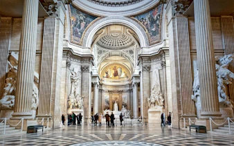 Interior of the Paris Pantheon with ornate columns and detailed sculptures.