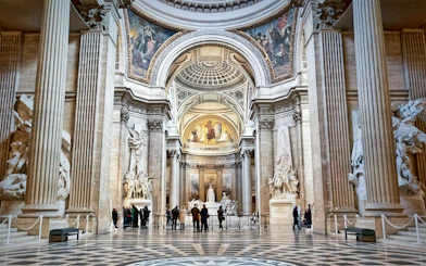 Interior of the Paris Pantheon with ornate columns and detailed sculptures.