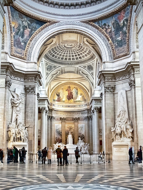 Interior of the Paris Pantheon with ornate columns and detailed sculptures.