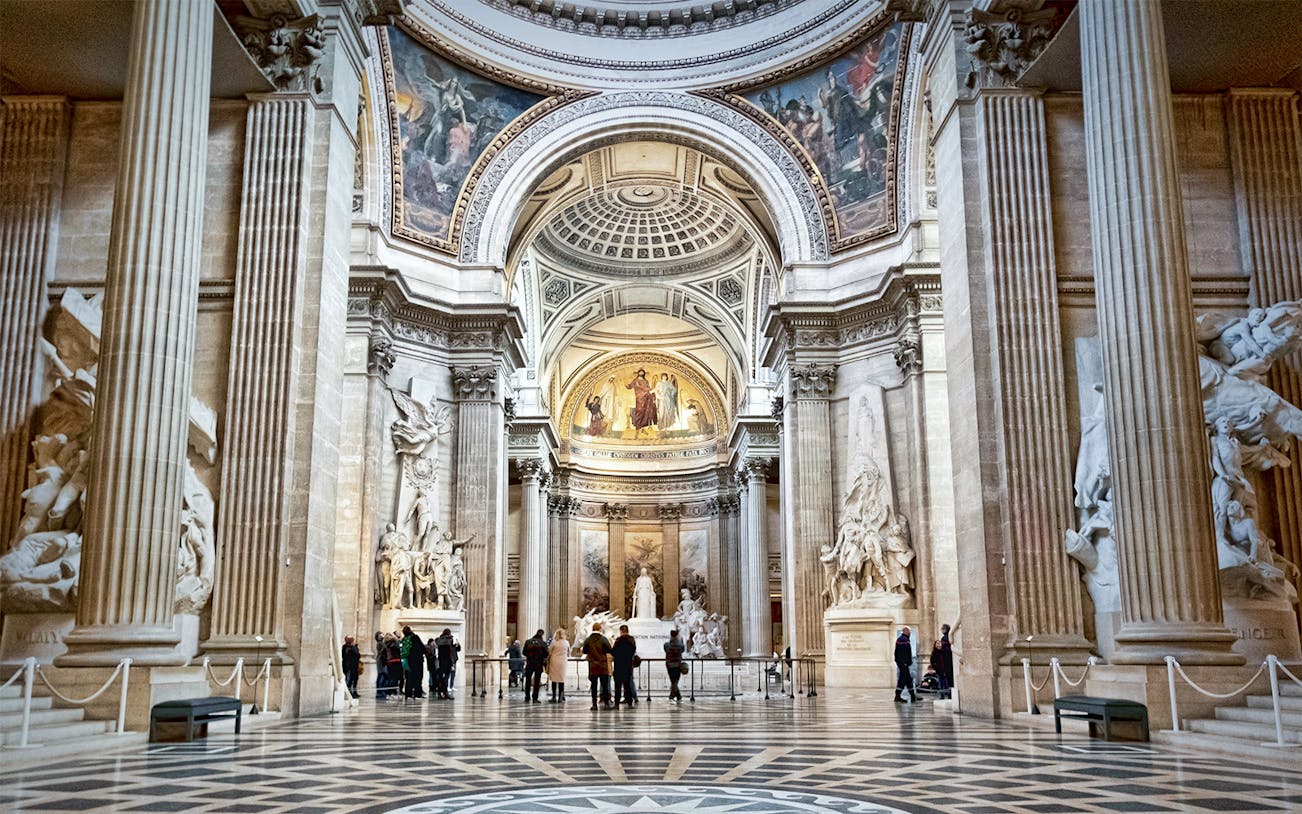 Interior of the Paris Pantheon with ornate columns and detailed sculptures.
