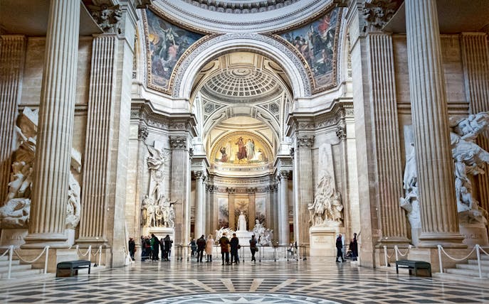 Interior of the Paris Pantheon with ornate columns and detailed sculptures.