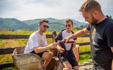 Men enjoying a drink tasting in Zakopane with mountain views.