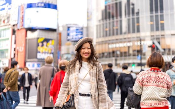 Person smiling at Shibuya Crossing in Tokyo during a personalized photoshoot.