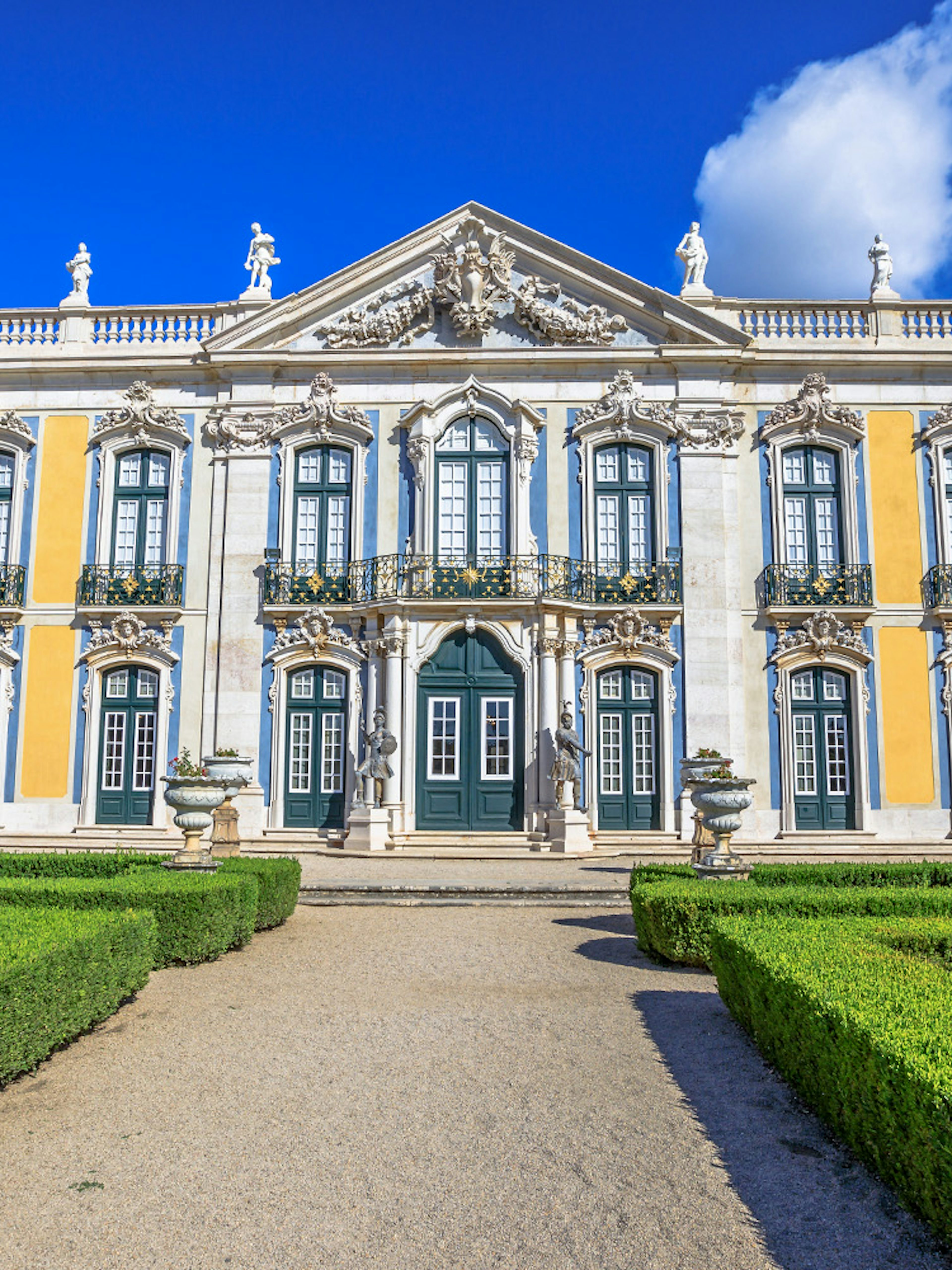 Facade of Queluz National Palace with ornate windows and manicured gardens.