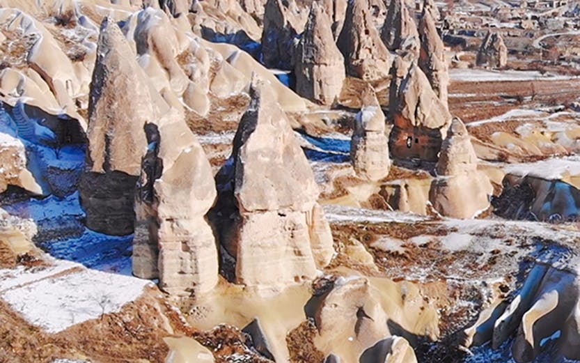 Fairy chimneys in Goreme Valley, Cappadocia, with snow-dusted rock formations.