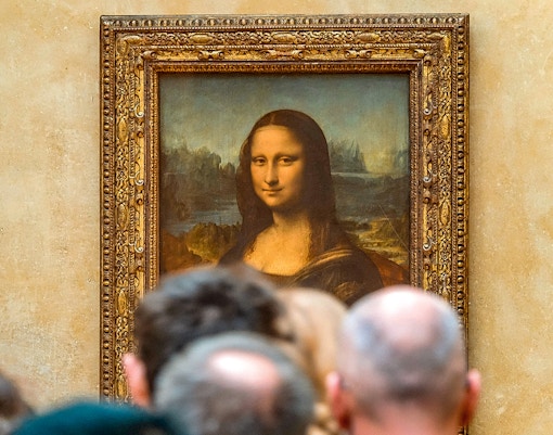 Tourists viewing artwork inside the Louvre Museum, Paris with reserved access tickets.