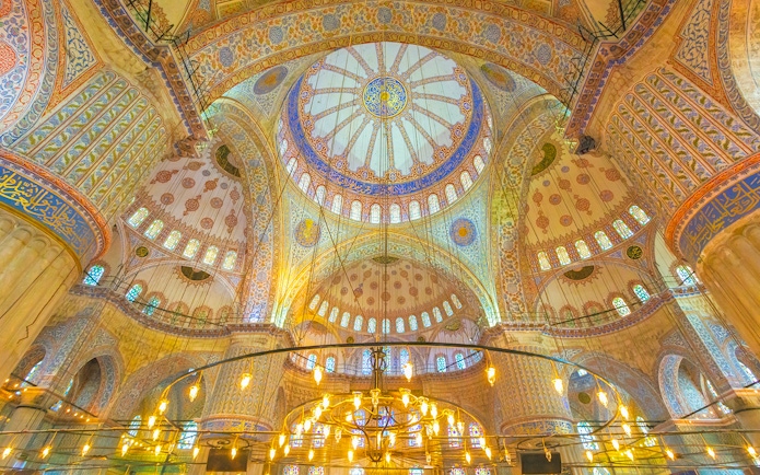 Interior view of the Blue Mosque dome in Istanbul, showcasing intricate patterns and stained glass.