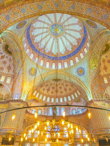 Interior view of the Blue Mosque dome in Istanbul, showcasing intricate patterns and stained glass.