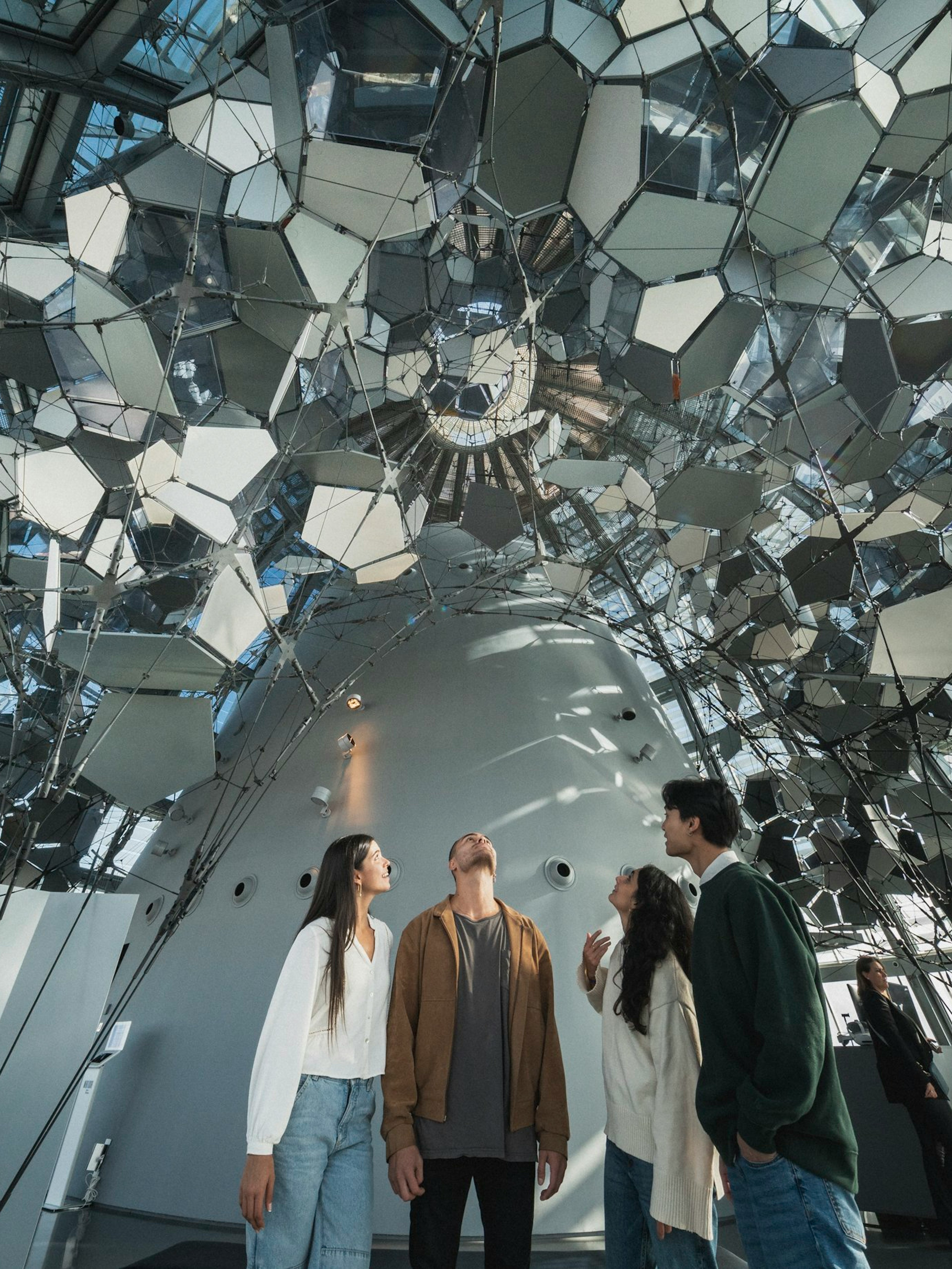 Visitors inside Glories Skyline Tower observing mirrored ceiling installation.