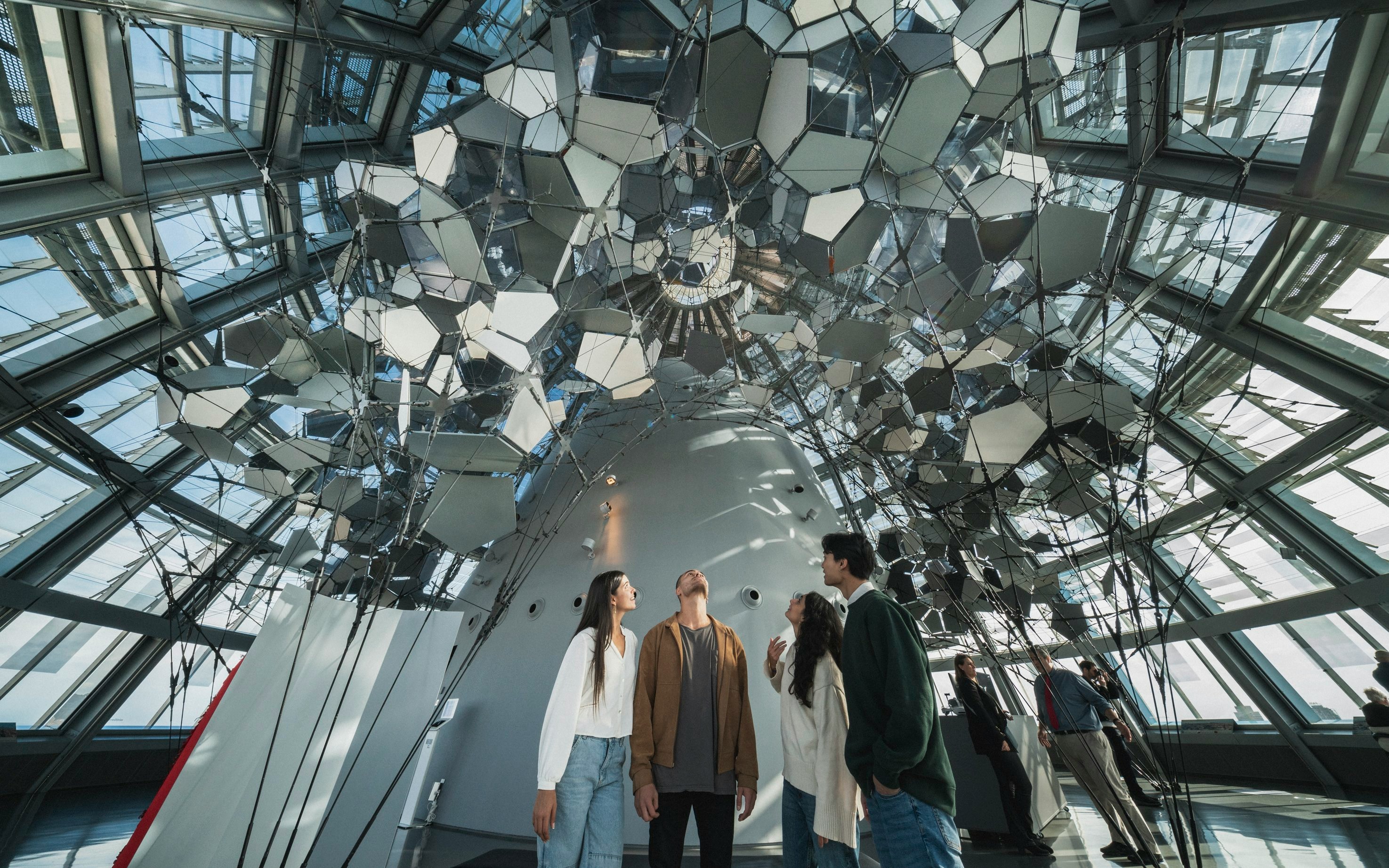Visitors inside Glories Skyline Tower observing mirrored ceiling installation.