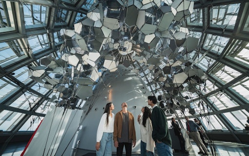 Visitors inside Glories Skyline Tower observing mirrored ceiling installation.