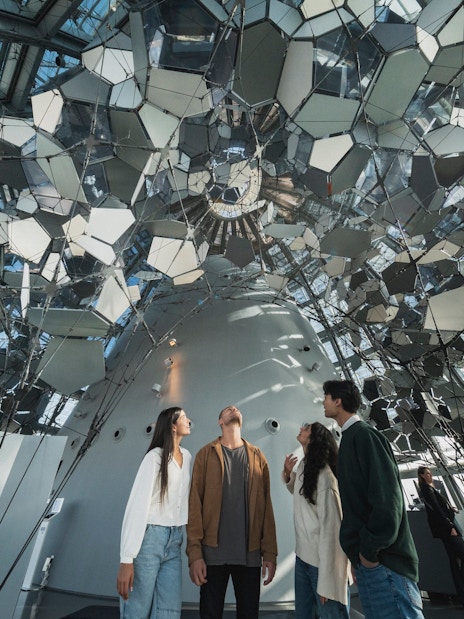 Visitors inside Glories Skyline Tower observing mirrored ceiling installation.