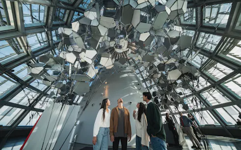 Visitors inside Glories Skyline Tower observing mirrored ceiling installation.