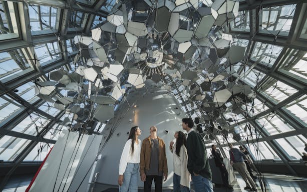 Visitors inside Glories Skyline Tower observing mirrored ceiling installation.