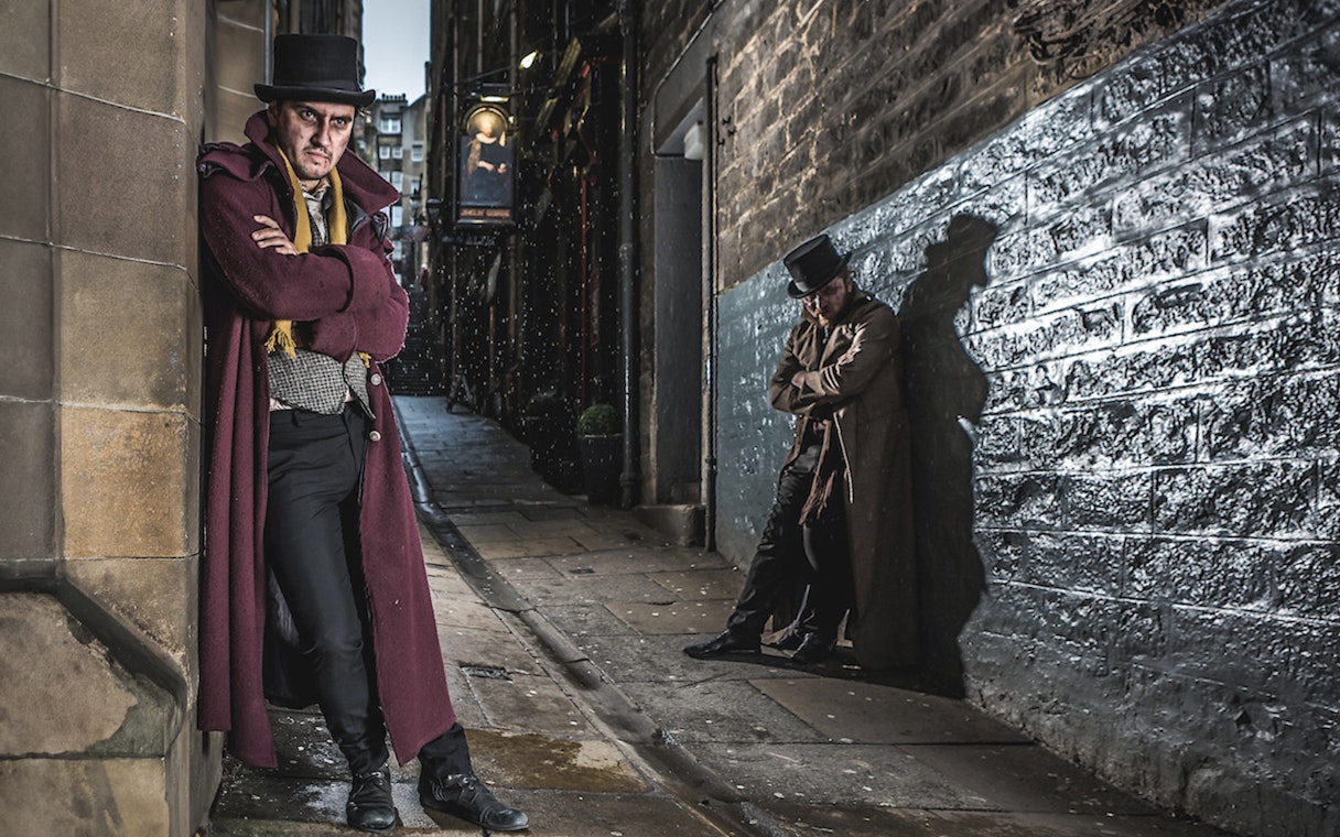 Victorian-costumed actors in a dim Edinburgh alley for the Dungeon Tour.