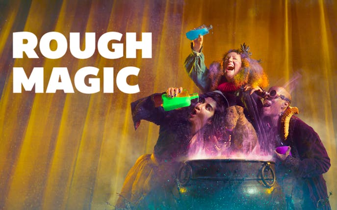 Three performers with colorful costumes and potions around a cauldron, "Rough Magic" text.