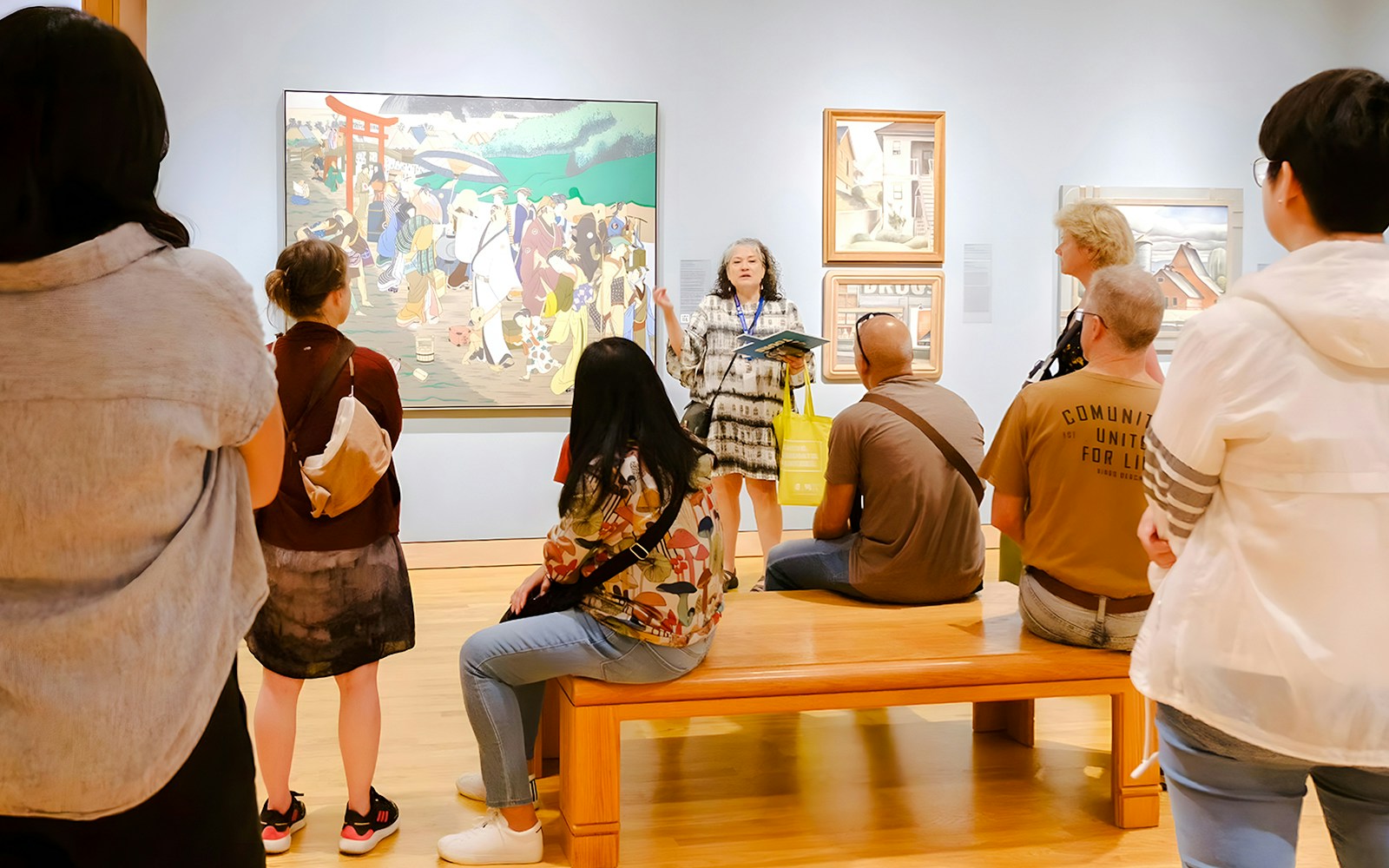 Visitors listening to a guide at Seattle Art Museum in front of a large painting.