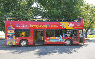 City Sightseeing hop on hop off tour bus in Corfu parked under trees.