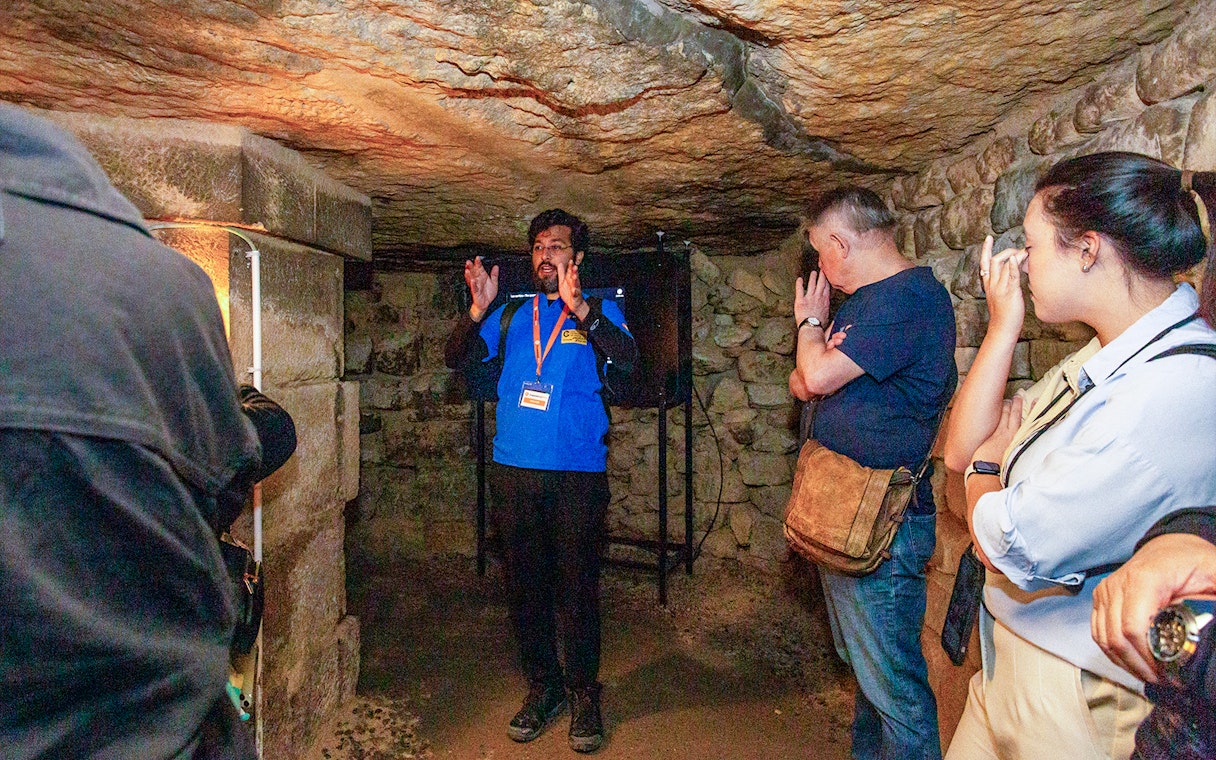 Guide explaining history to visitors inside Paris Catacombs.