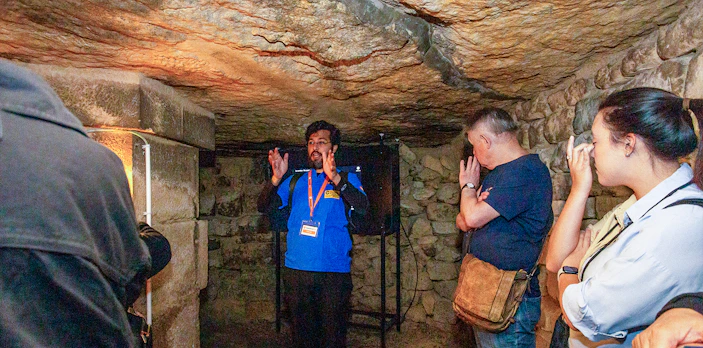 Guide explaining history to visitors inside Paris Catacombs.