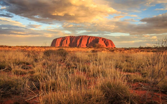 Uluru at sunset with cloudy sky, viewed from Alice Springs tour.
