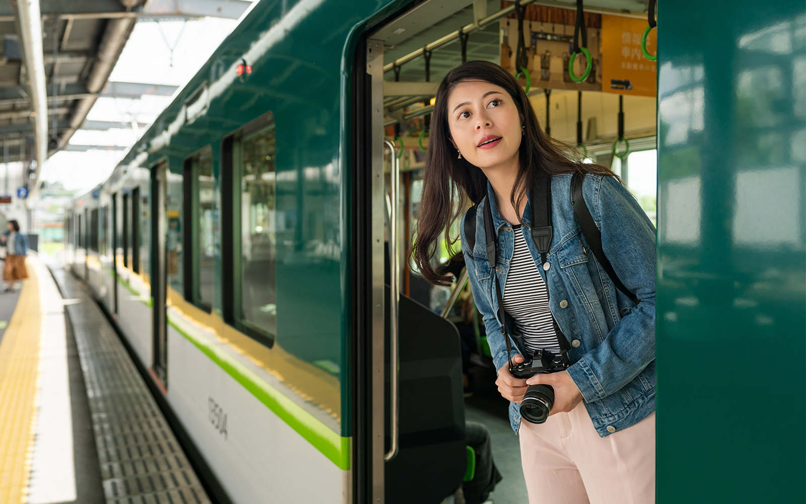 Visitor with camera exiting train in Osaka using JR-West Kansai Area Rail Pass.