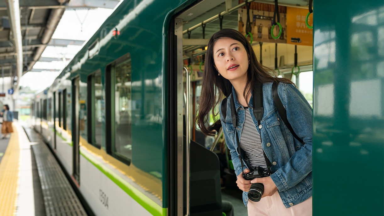 Visitor with camera exiting train in Osaka using JR-West Kansai Area Rail Pass.