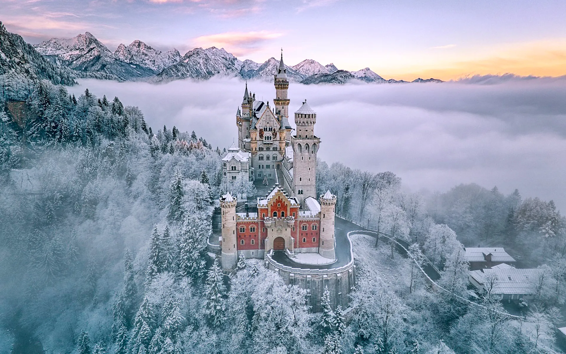 Neuschwanstein Castle surrounded by snow-covered trees and mountains in Bavaria, Germany.