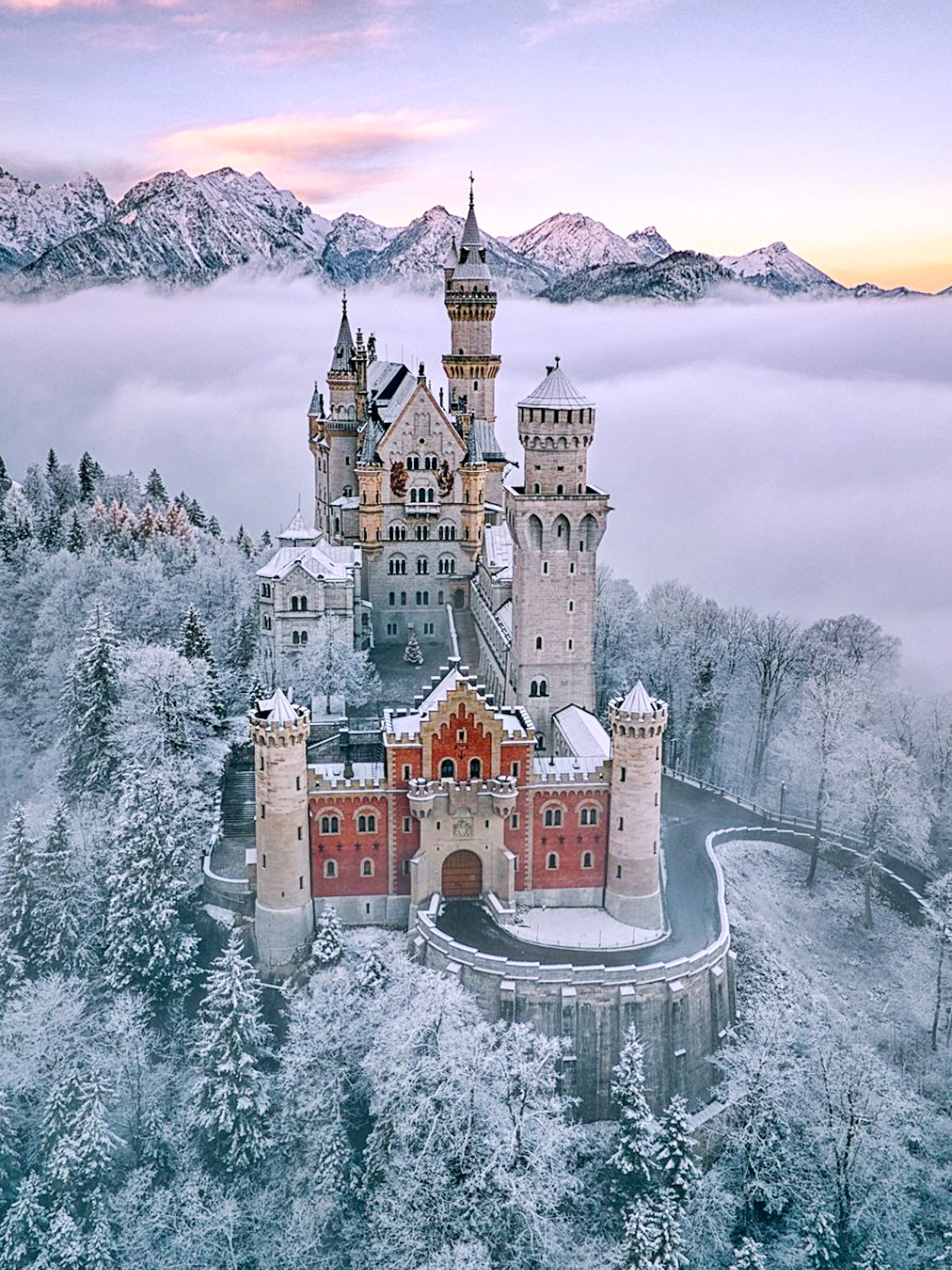 Neuschwanstein Castle surrounded by snow-covered trees and mountains in Bavaria, Germany.