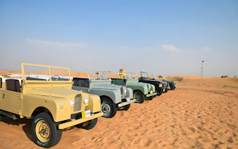 Vintage Land Rovers lined up in the desert for a hot air balloon experience.
