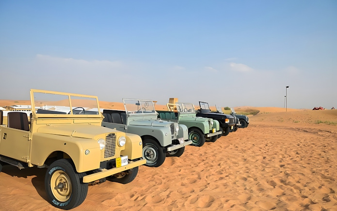 Vintage Land Rovers lined up in the desert for a hot air balloon experience.