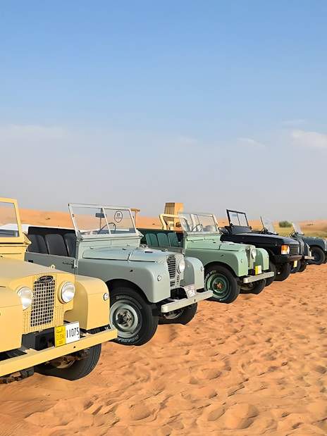 Vintage Land Rovers lined up in the desert for a hot air balloon experience.