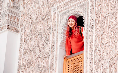 Woman looking out from ornate window at Ben Youssef Madrasa, Marrakech, Morocco.