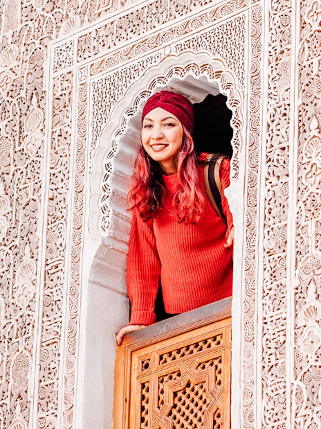 Woman looking out from ornate window at Ben Youssef Madrasa, Marrakech, Morocco.