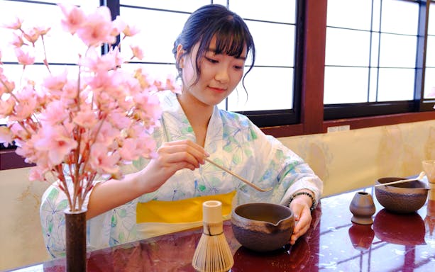 Woman in kimono preparing tea during Tokyo spring tea ceremony.