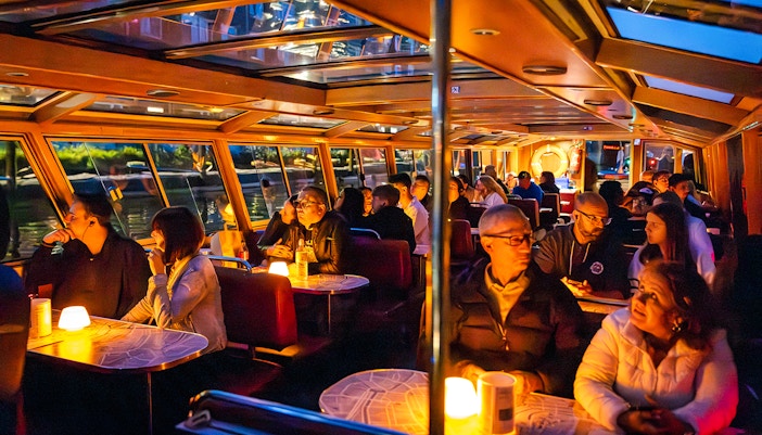 Guests enjoying a cozy evening cruise on a canal boat in Amsterdam.