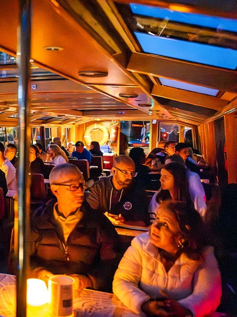 Guests enjoying a cozy evening cruise on a canal boat in Amsterdam.