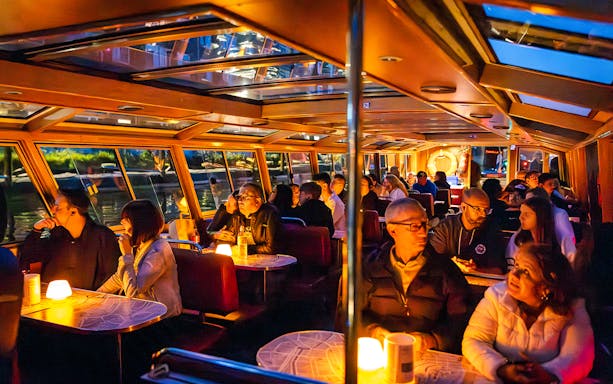 Guests enjoying a cozy evening cruise on a canal boat in Amsterdam.