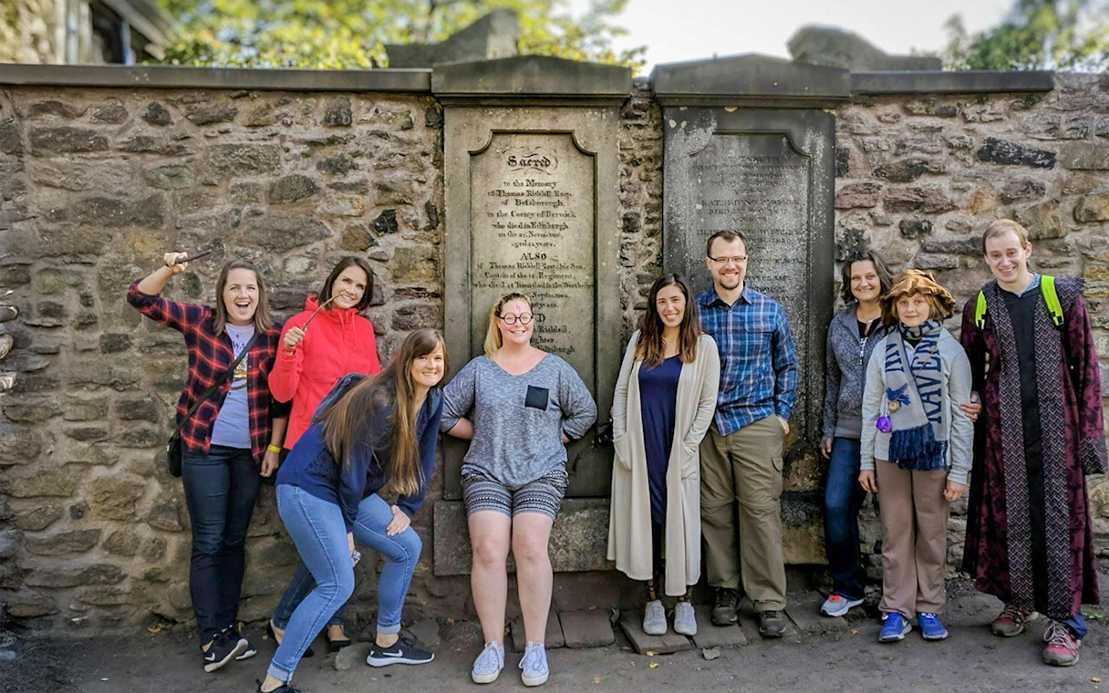 Group posing with wands at Greyfriars Kirkyard on a Harry Potter walking tour in Edinburgh.