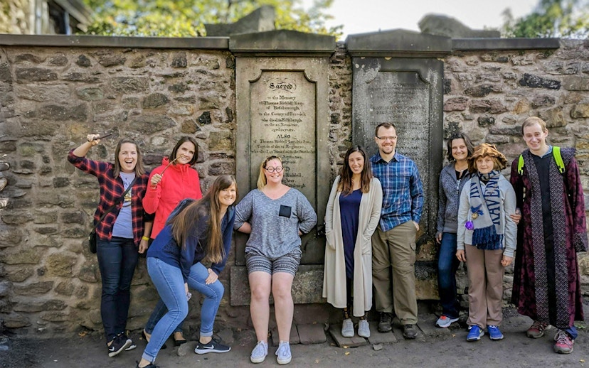 Group posing with wands at Greyfriars Kirkyard on a Harry Potter walking tour in Edinburgh.