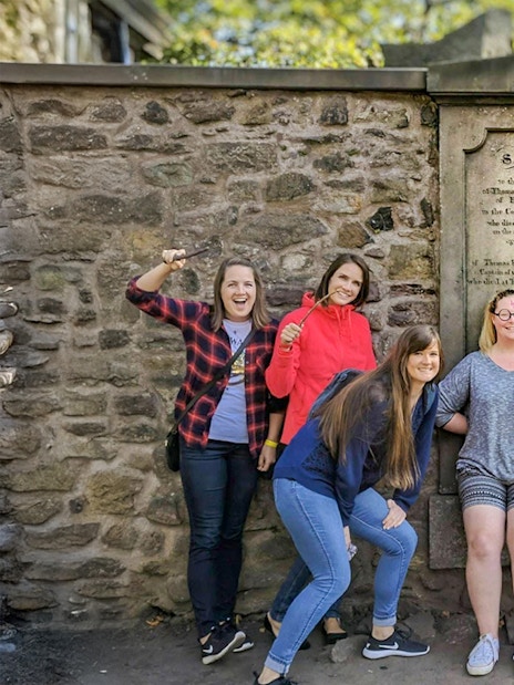 Group posing with wands at Greyfriars Kirkyard on a Harry Potter walking tour in Edinburgh.