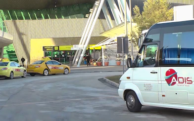 Bus and taxis at Tirana Airport entrance for Durres transfer service.