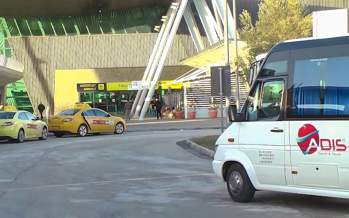 Bus and taxis at Tirana Airport entrance for Durres transfer service.