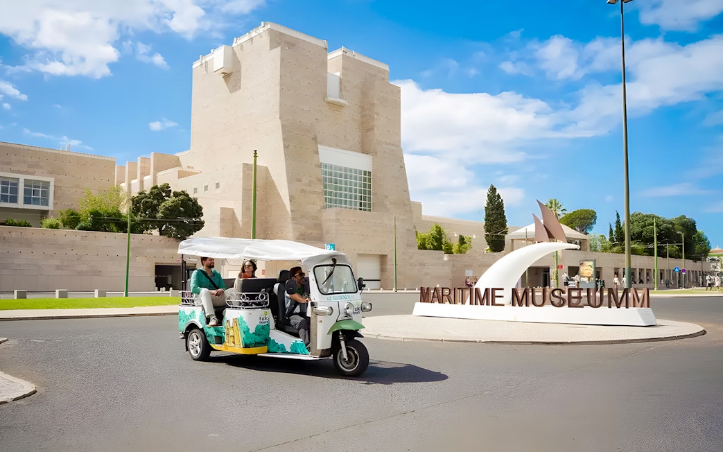 Tourist on eco tuk-tuk passing by Maritime Museum in Lisbon.