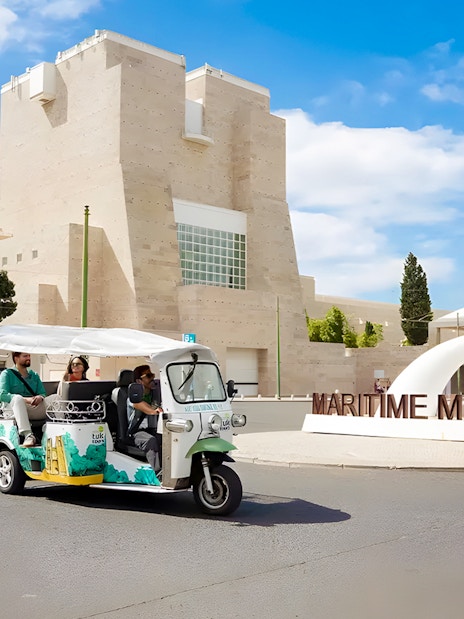Tourist on eco tuk-tuk passing by Maritime Museum in Lisbon.