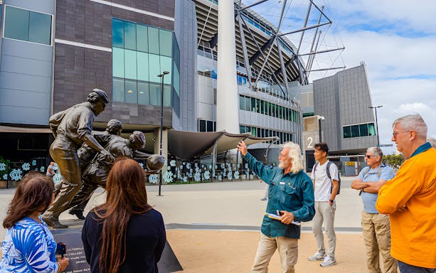 Guide explaining statue to visitors at Melbourne Cricket Ground, Melbourne.