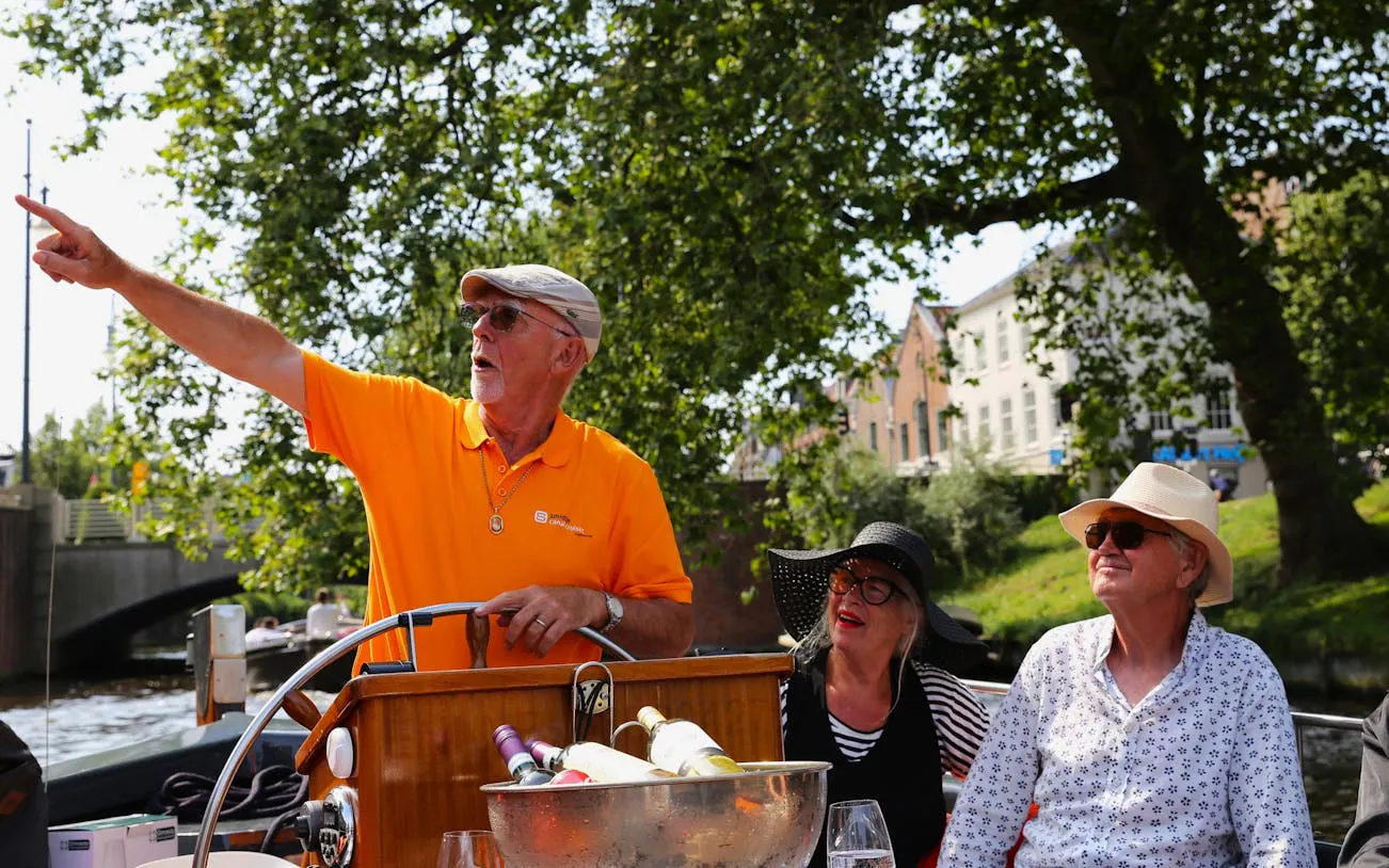 Skipper giving commentary on Haarlem canal cruise with passengers listening.