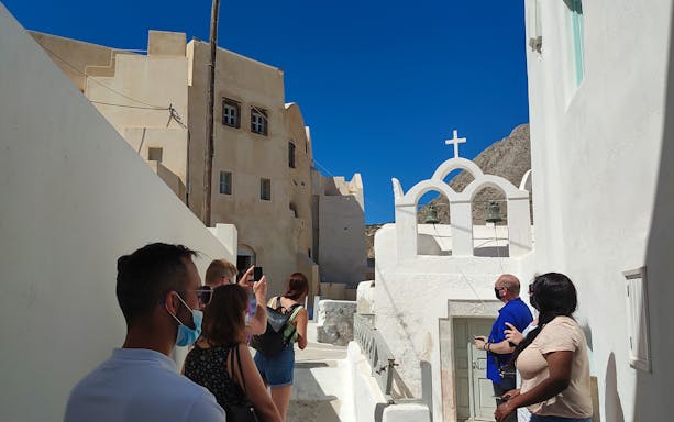 Tourists exploring narrow streets and traditional architecture in Emporio, Santorini.