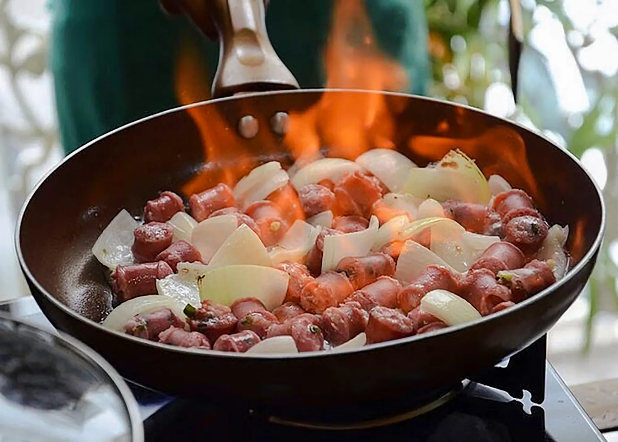 Sausages and onions cooking in a flaming pan during a Brazilian cooking class in Copacabana, Rio de Janeiro.